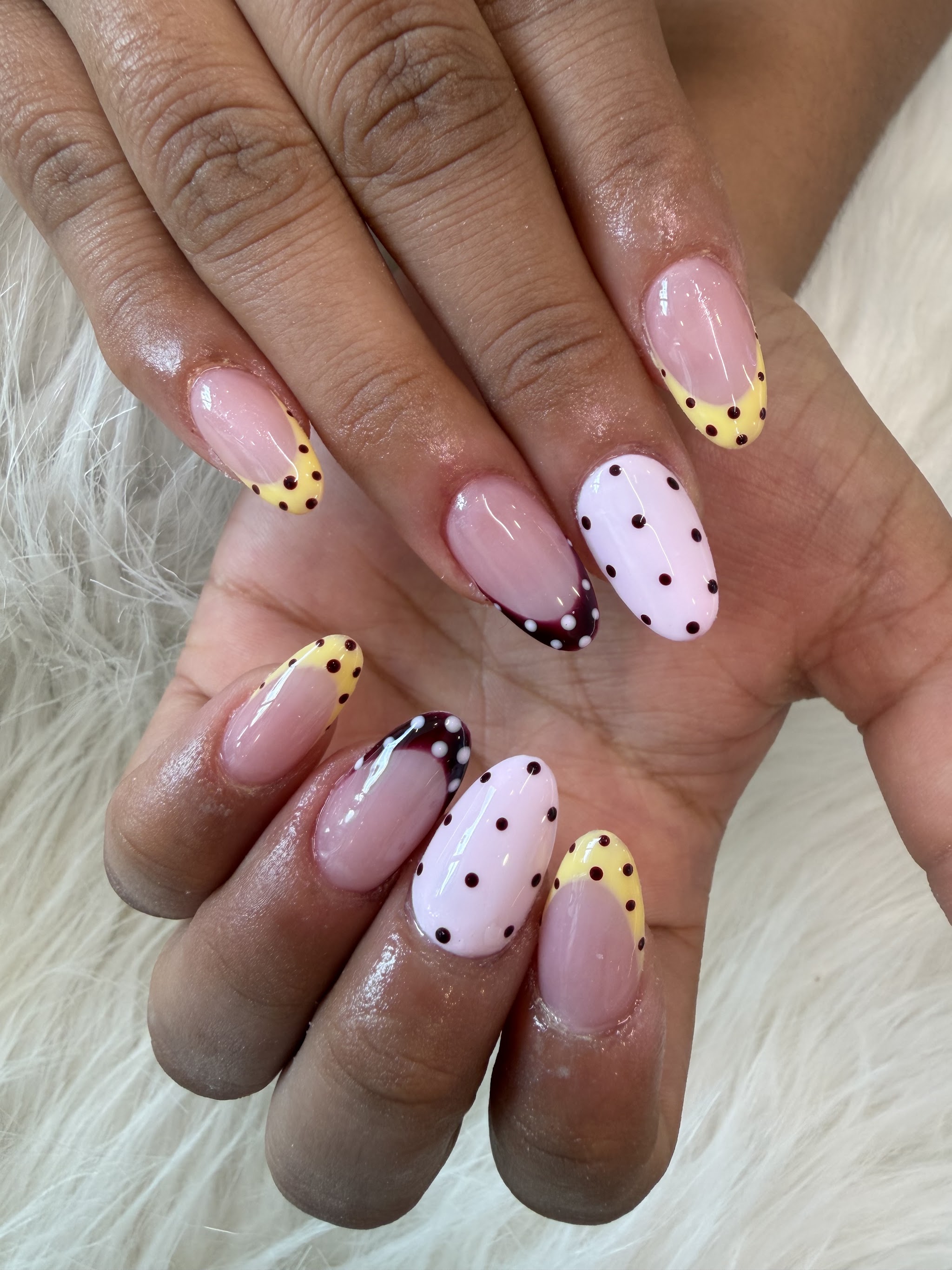 Yellow, pink and burgundy polka-dot French tips in an almond shape