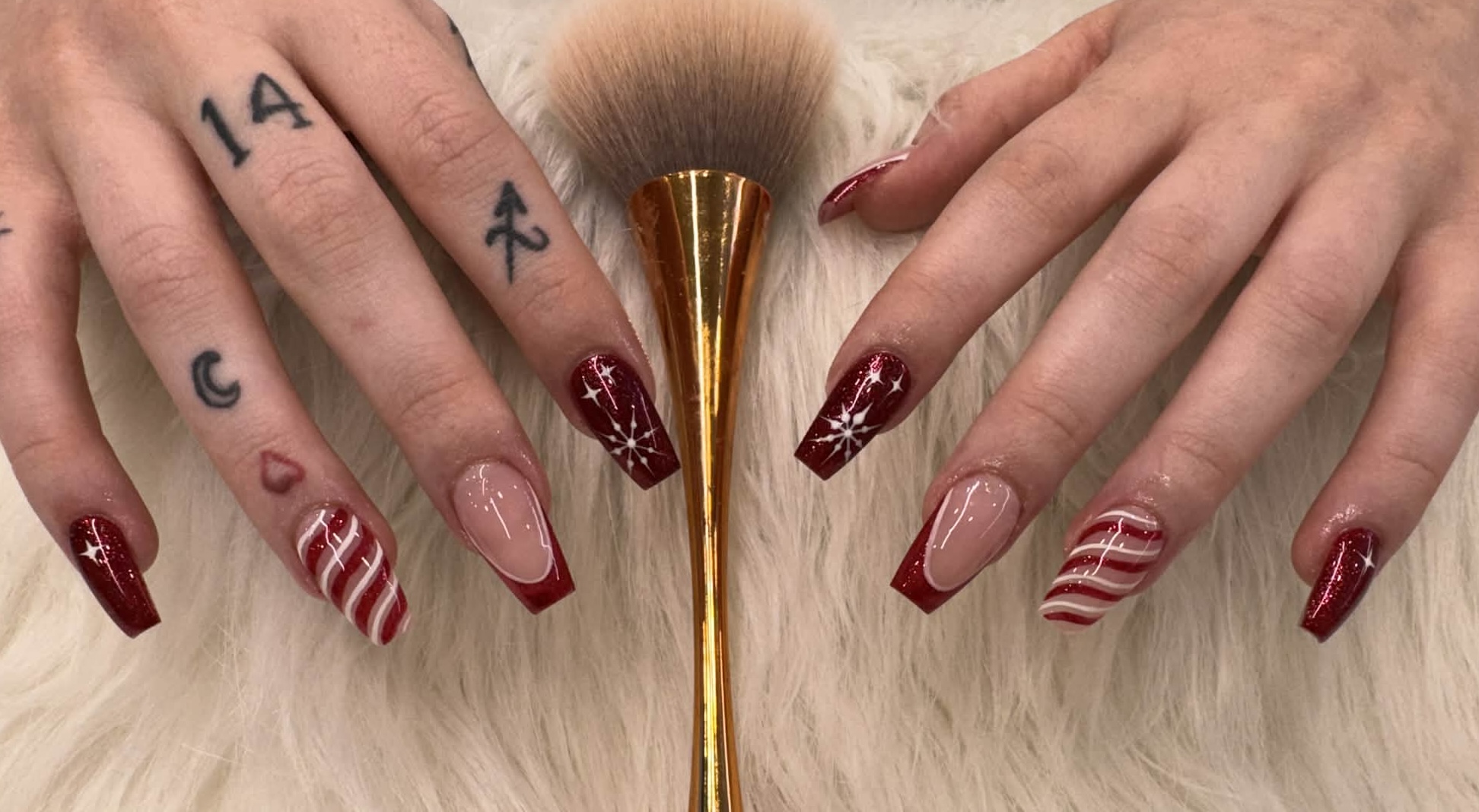 Red glitter nails with candy-cane stripes and snowflake line art, coffin shape